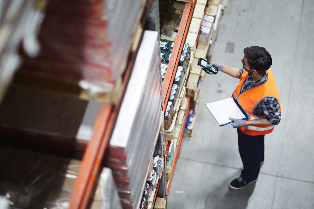 AdobeStock_151809562_ Worker with scanner making review of goods in warehouse